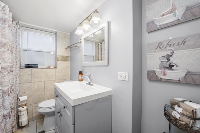bathroom featuring vanity, tile patterned flooring, toilet, and tile walls