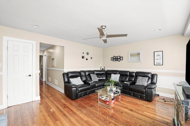living area with baseboards, a ceiling fan, wood finished floors, and visible vents