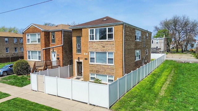 view of front of property featuring fence private yard, brick siding, and a front yard