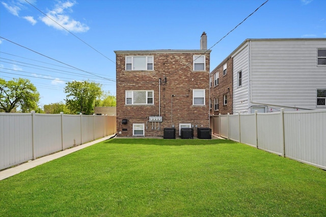 back of house featuring a fenced backyard, central AC unit, a yard, and brick siding
