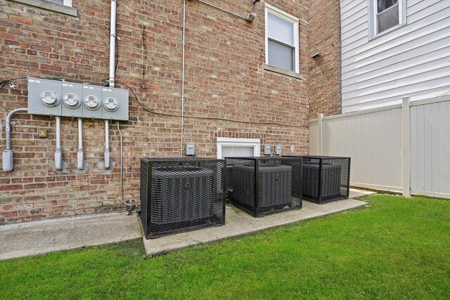 exterior details featuring central air condition unit, brick siding, fence, and electric meter
