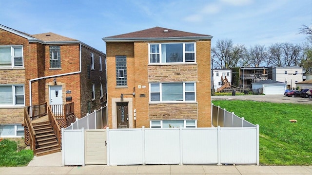 view of front of home featuring brick siding, a front yard, fence private yard, and stone siding