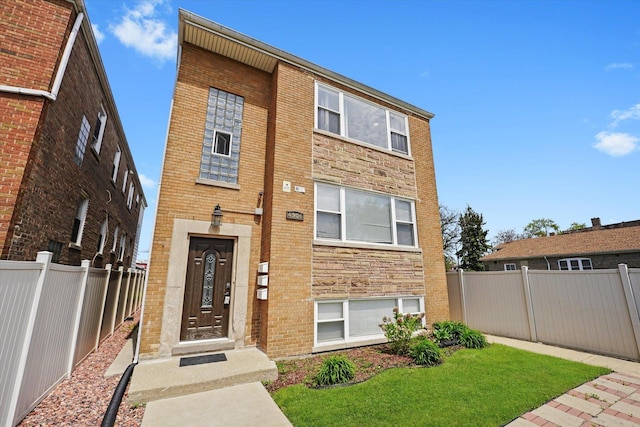 view of front of home with brick siding, fence private yard, and a front yard