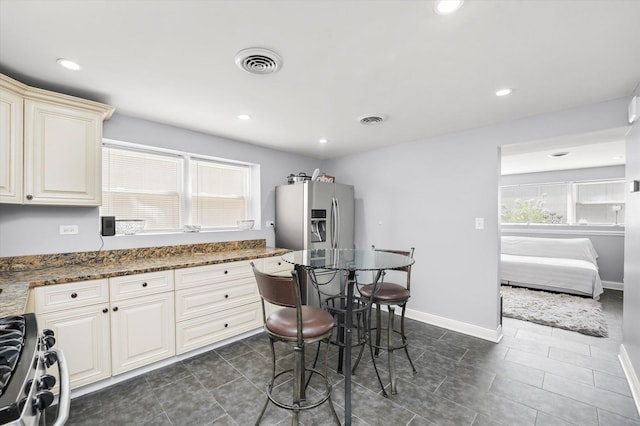 kitchen with dark tile patterned flooring, appliances with stainless steel finishes, a wealth of natural light, and visible vents