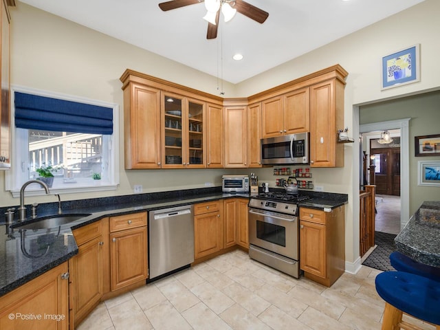 kitchen with ceiling fan, appliances with stainless steel finishes, brown cabinetry, and a sink