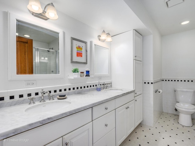 bathroom with toilet, tile walls, a shower stall, and a sink