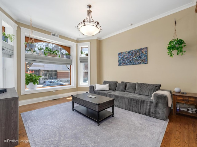 living room with crown molding, baseboards, visible vents, and wood finished floors