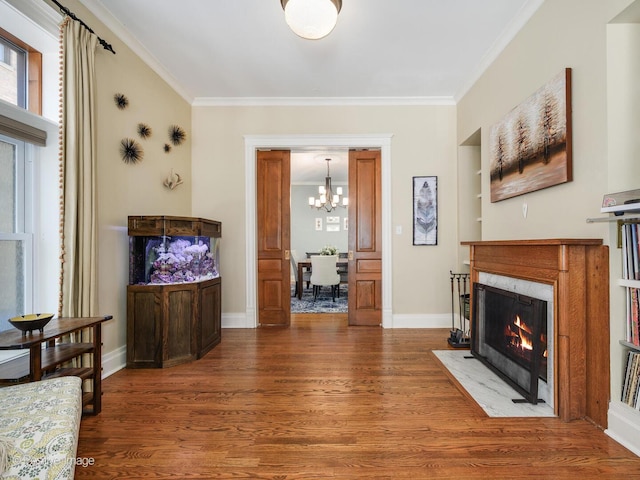 living area with ornamental molding, a fireplace with flush hearth, and wood finished floors