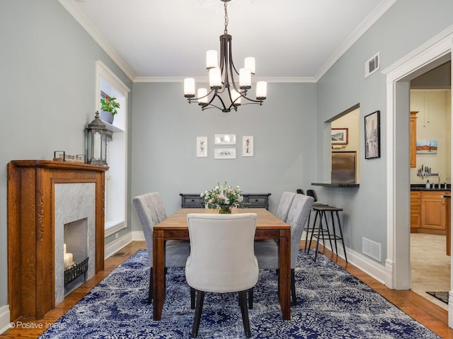 dining area featuring ornamental molding, a notable chandelier, light wood-style flooring, and visible vents