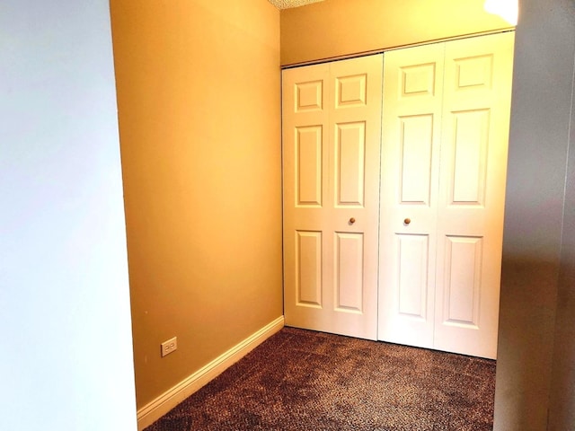 unfurnished bedroom with dark carpet and a closet