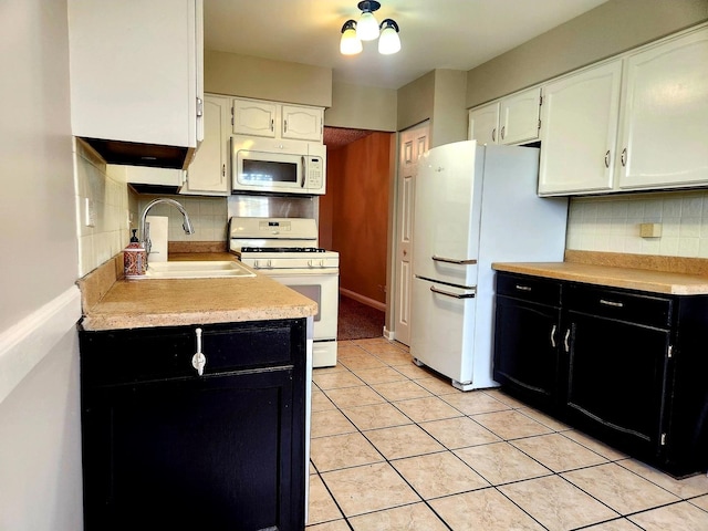 kitchen featuring white appliances, dark cabinets, white cabinetry, a sink, and light countertops