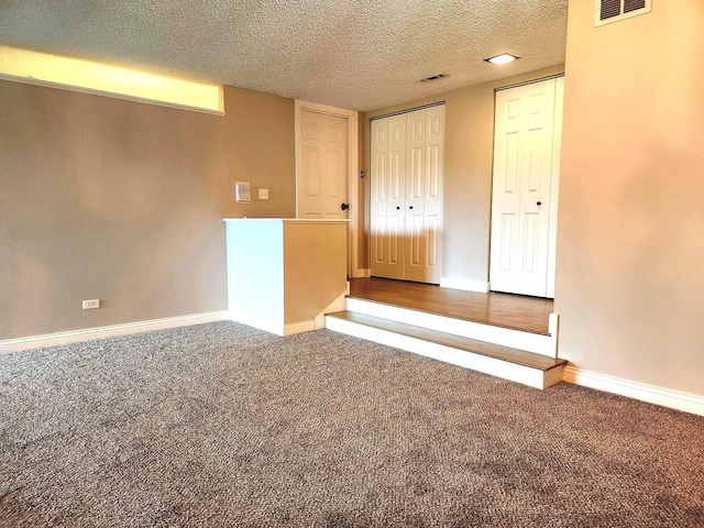 spare room with carpet flooring, a textured ceiling, and baseboards