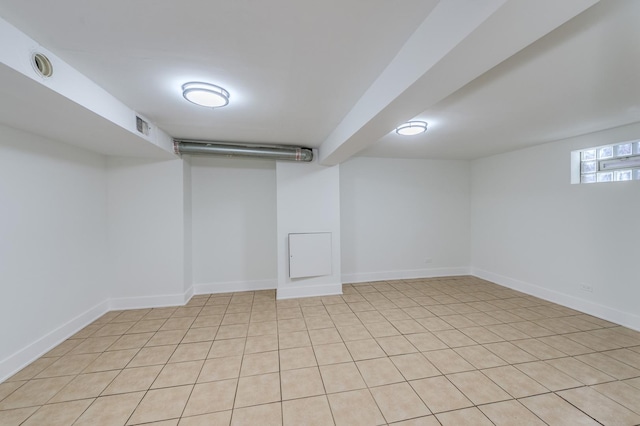 below grade area featuring baseboards, visible vents, and light tile patterned flooring