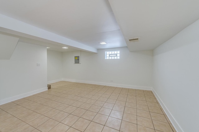 basement with electric panel, baseboards, visible vents, and light tile patterned floors