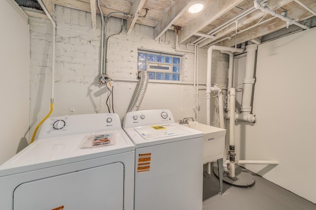clothes washing area featuring laundry area, a sink, and washer and clothes dryer