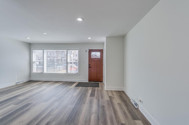 foyer featuring baseboards, wood finished floors, visible vents, and recessed lighting