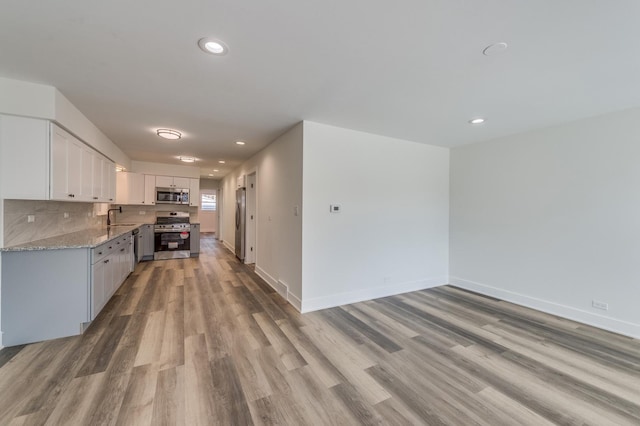 kitchen featuring light wood-style flooring, a sink, recessed lighting, white cabinetry, and appliances with stainless steel finishes