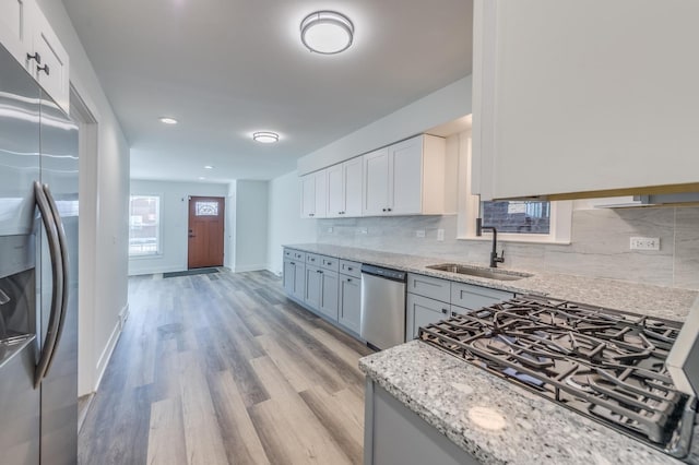 kitchen with decorative backsplash, light stone counters, a sink, and appliances with stainless steel finishes