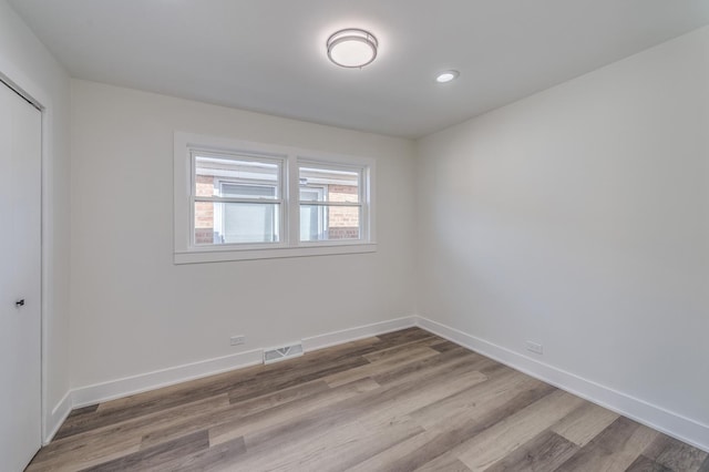 spare room featuring baseboards, wood finished floors, visible vents, and recessed lighting