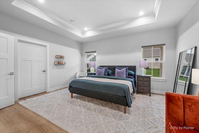 bedroom featuring recessed lighting, a raised ceiling, ornamental molding, light wood-type flooring, and baseboards