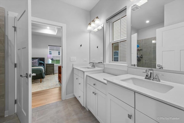 bathroom featuring a tile shower, visible vents, two vanities, and a sink