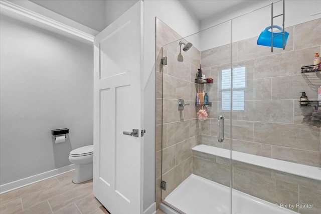bathroom with a shower stall, toilet, tile patterned floors, and baseboards