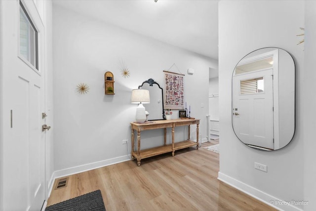 foyer entrance with light wood-style flooring, visible vents, and baseboards