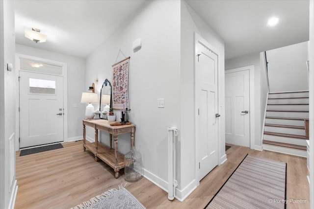 entryway with light wood-style flooring, baseboards, and stairs