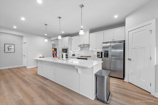 kitchen featuring white cabinets, an island with sink, under cabinet range hood, light wood-type flooring, and appliances with stainless steel finishes