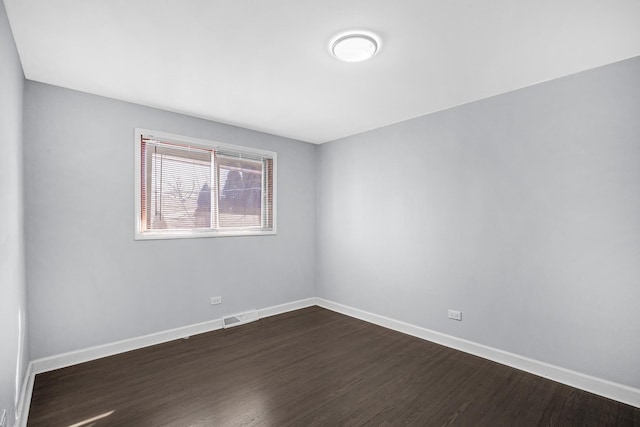 spare room with baseboards, dark wood finished floors, and visible vents