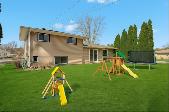 rear view of house featuring a lawn, a playground, and a trampoline