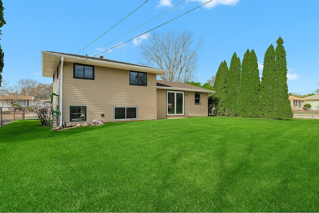 rear view of house featuring fence and a yard
