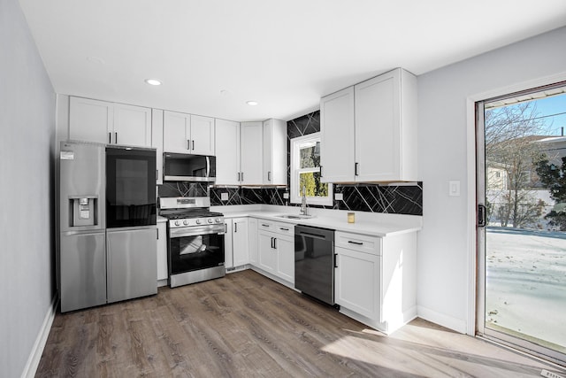 kitchen featuring a sink, backsplash, white cabinetry, and stainless steel appliances