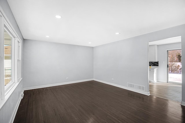 unfurnished room with dark wood-type flooring, visible vents, baseboards, and recessed lighting