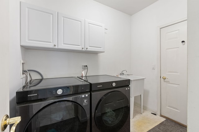 clothes washing area featuring separate washer and dryer, baseboards, and cabinet space