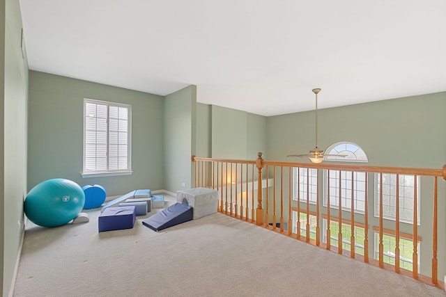 exercise area featuring carpet flooring, a ceiling fan, and baseboards