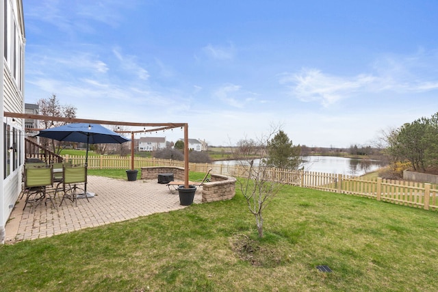 view of yard featuring a fenced backyard, a fire pit, a water view, and a patio area