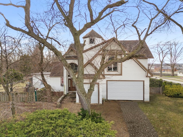 traditional home with a garage, driveway, a shingled roof, and fence