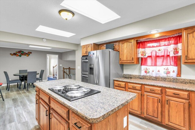 3104 Park Haven Blvd, Danville, IL 61832 - kitchen featuring appliances with stainless steel finishes, a skylight, brown cabinetry, and a kitchen island