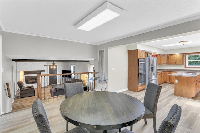 3104 Park Haven Blvd, Danville, IL 61832 - dining space with light wood finished floors, crown molding, a fireplace, baseboards, and ceiling fan