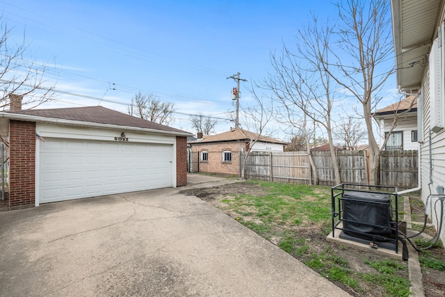 view of yard featuring a detached garage, fence, and an outbuilding