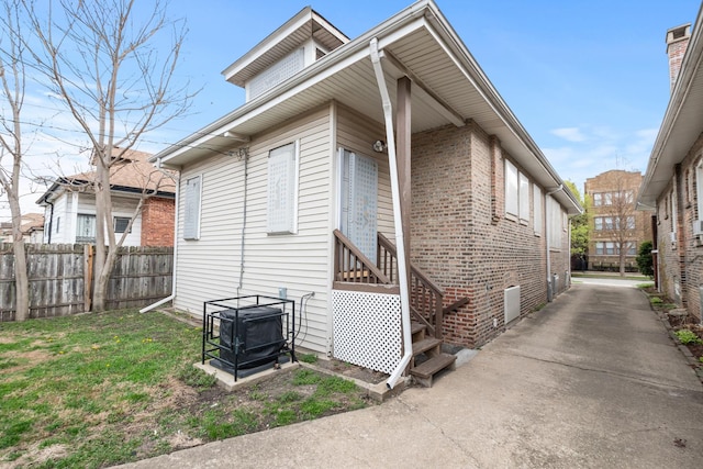 view of property exterior featuring brick siding and fence