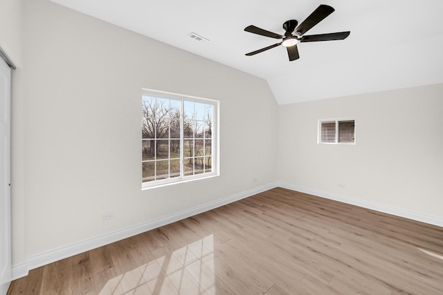 unfurnished room featuring lofted ceiling, wood finished floors, visible vents, baseboards, and ceiling fan