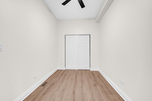 unfurnished bedroom featuring light wood finished floors, baseboards, visible vents, and a closet