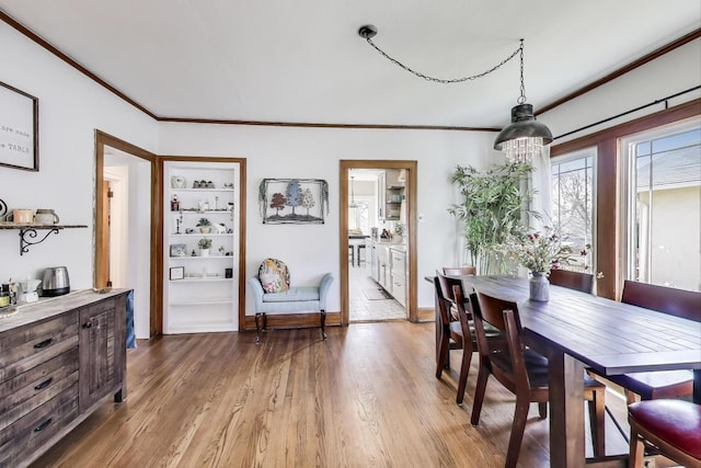 dining room with light wood finished floors, baseboards, and ornamental molding