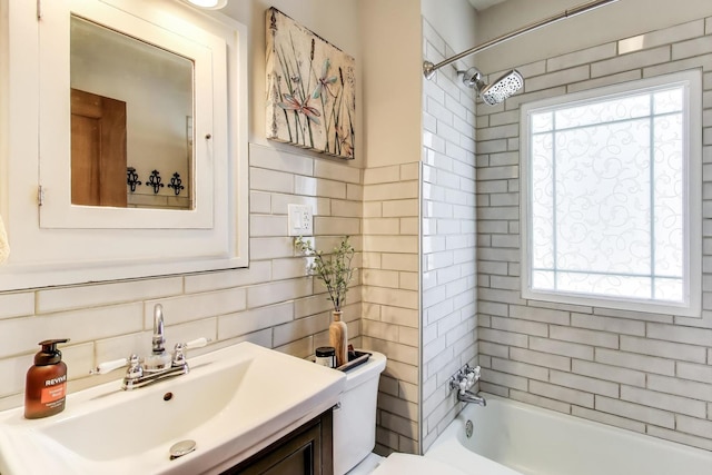 bathroom with toilet, tile walls, backsplash, vanity, and shower / tub combination