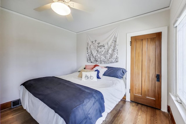 bedroom with wood finished floors, visible vents, crown molding, and a ceiling fan