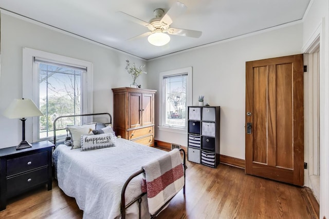 bedroom featuring a ceiling fan, crown molding, wood finished floors, and visible vents