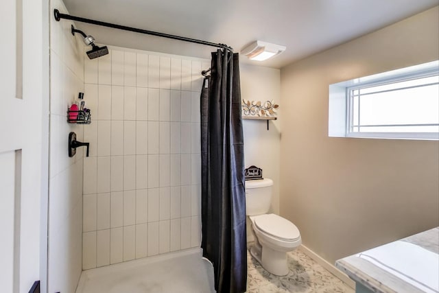 bathroom featuring baseboards, toilet, and tiled shower