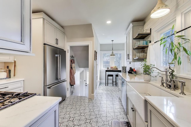 kitchen with recessed lighting, light stone counters, a sink, decorative light fixtures, and appliances with stainless steel finishes